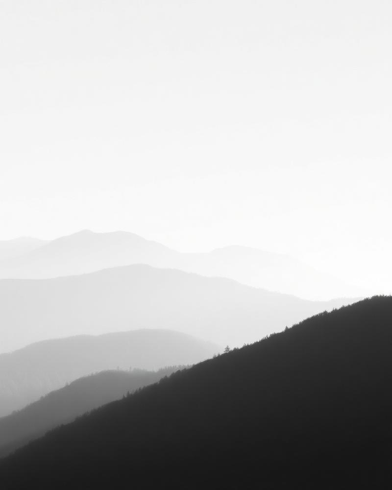 Monochrome landscape of mist layered over mountain ridges